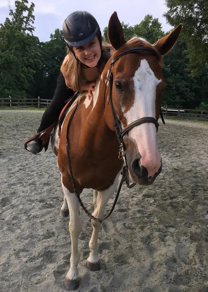 Girl on a horse bending down and smiling