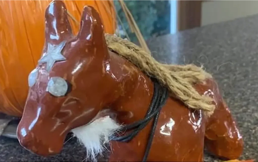 Pumpkin and ceramic horse decorations sitting on a wooden table